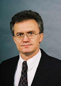 Mason associate professor Peter Pachowicz wears a dark suit and tie, glasses and white shirt in his faculty profile