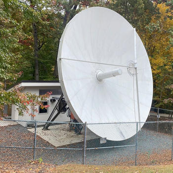 A white satellite dish inside a gated area outside